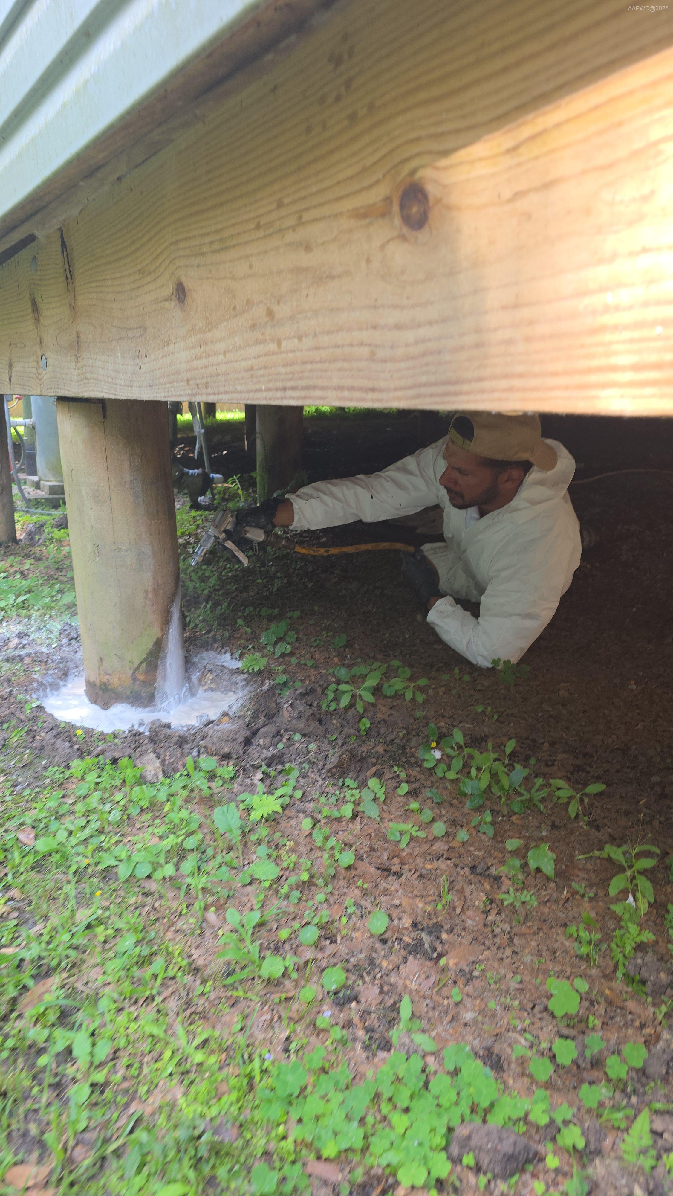 Professional termite treatment for a raised home on piers using liquid barrier protection around the foundation.